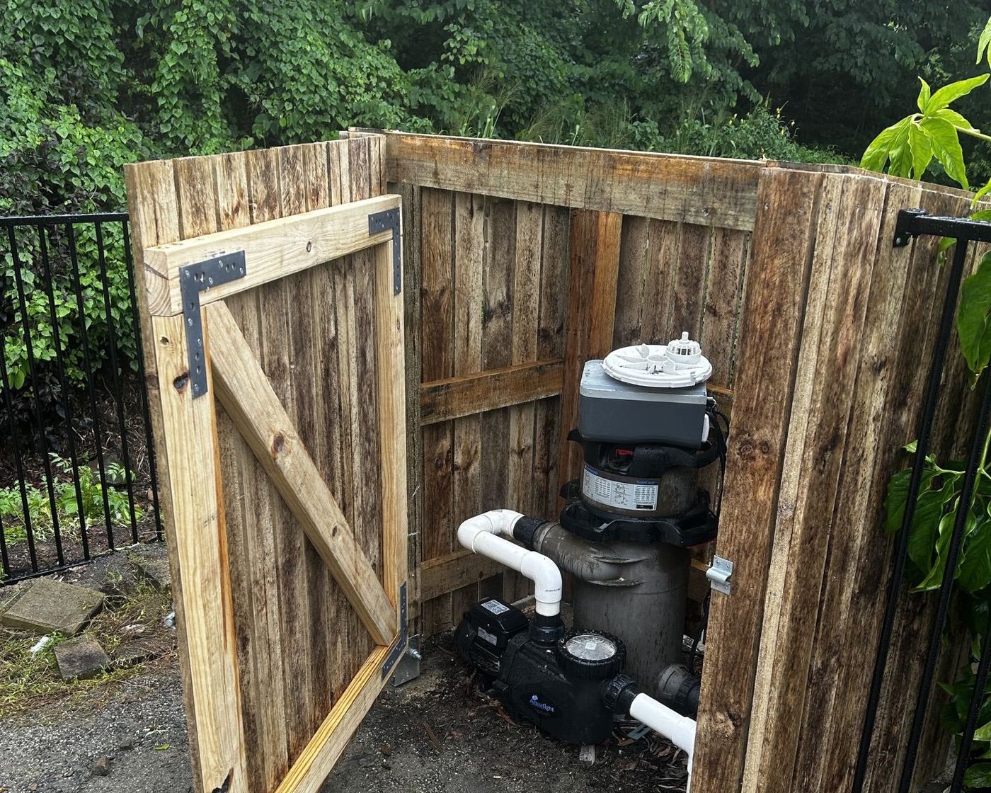 A timber gate standing open in a paling fence beside a garden path