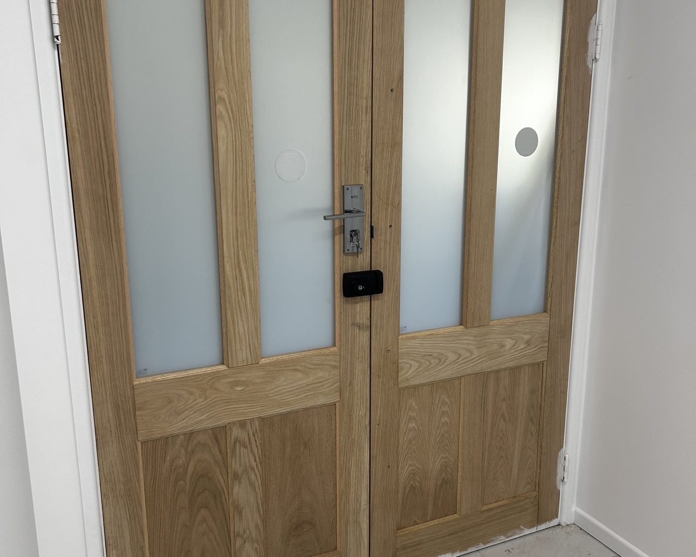 A pair of timber-framed internal doors with frosted glass panels in a hallway