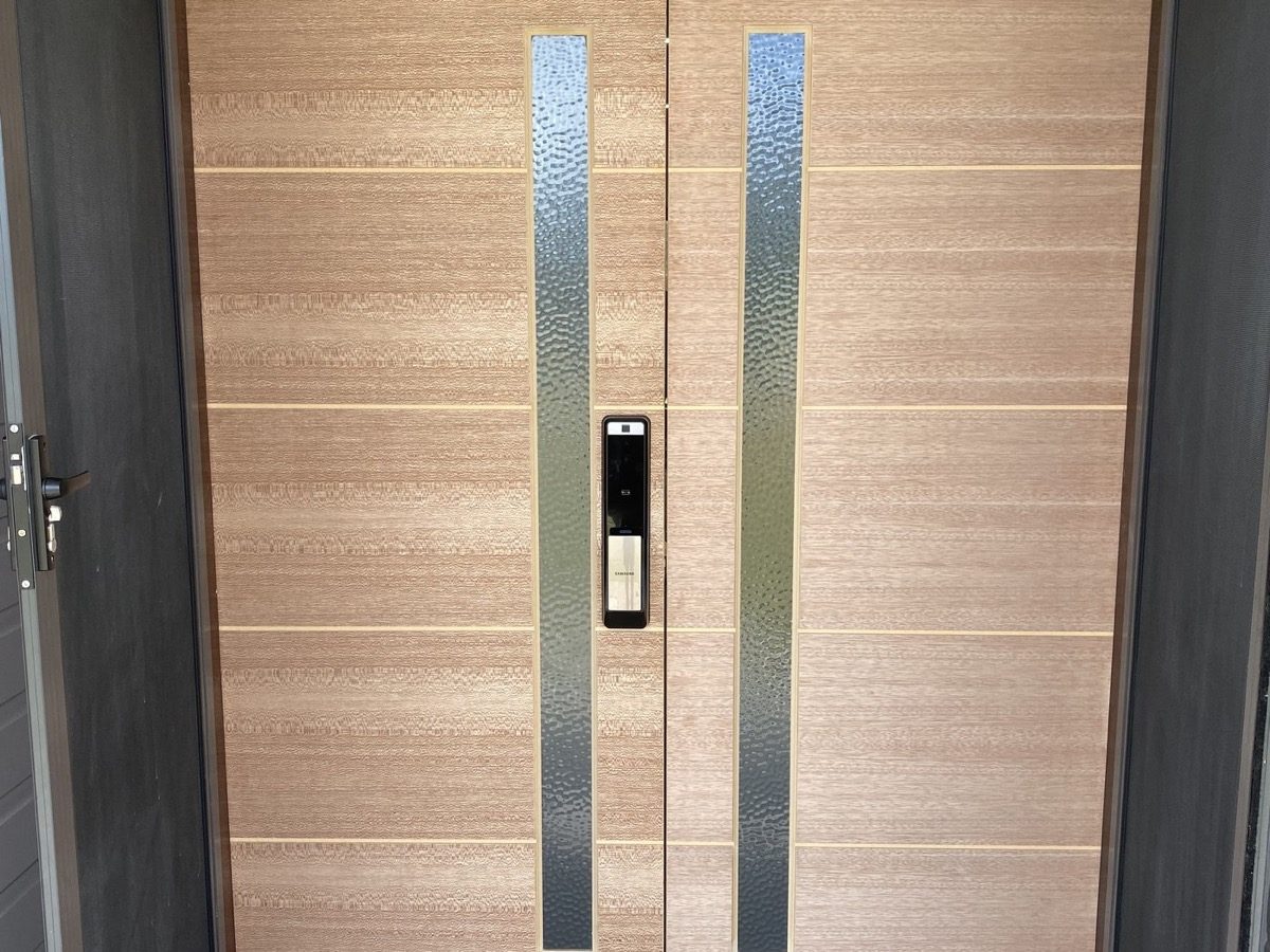 A wide timber pivot entry door with long vertical pull handles