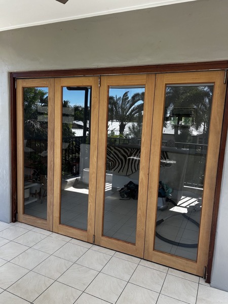 Timber-framed bifold doors opening from a tiled room out onto a deck