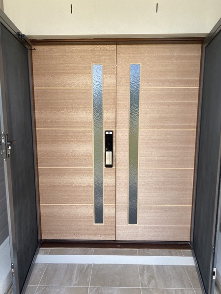 A wide timber pivot entry door with long vertical pull handles