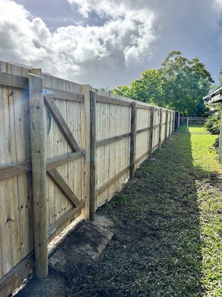 A capped timber paling fence running the length of a back lawn