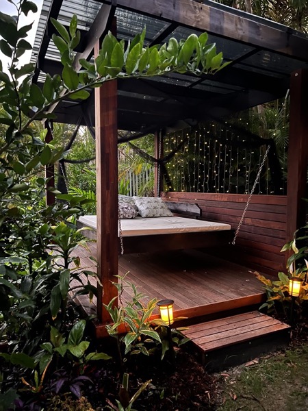 A hardwood pergola lit with string lights and lanterns at dusk