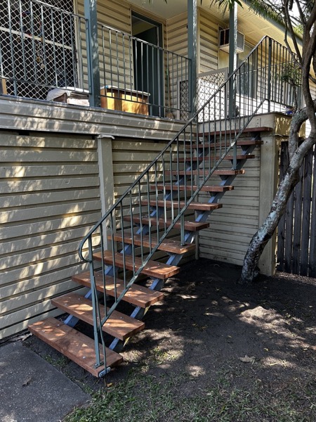 An external steel and timber staircase running up the side of a raised home