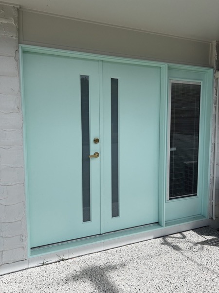 Painted double entry doors with vertical pull handles and a side panel