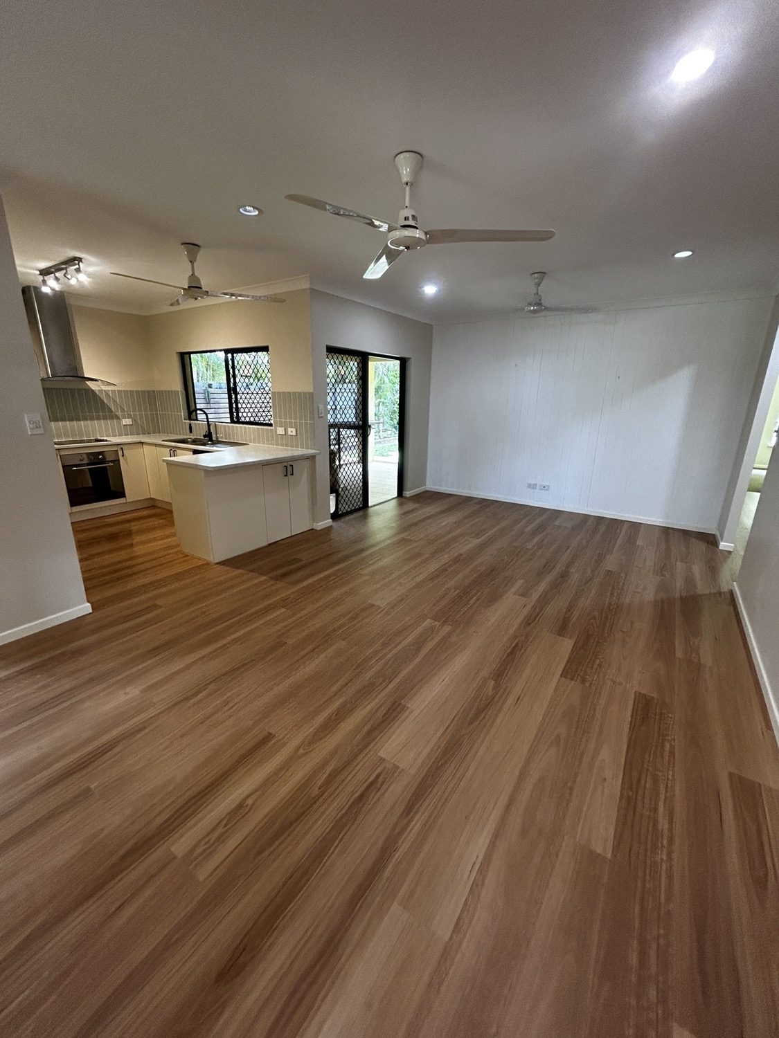 An open living room with new timber floorboards running through to the kitchen